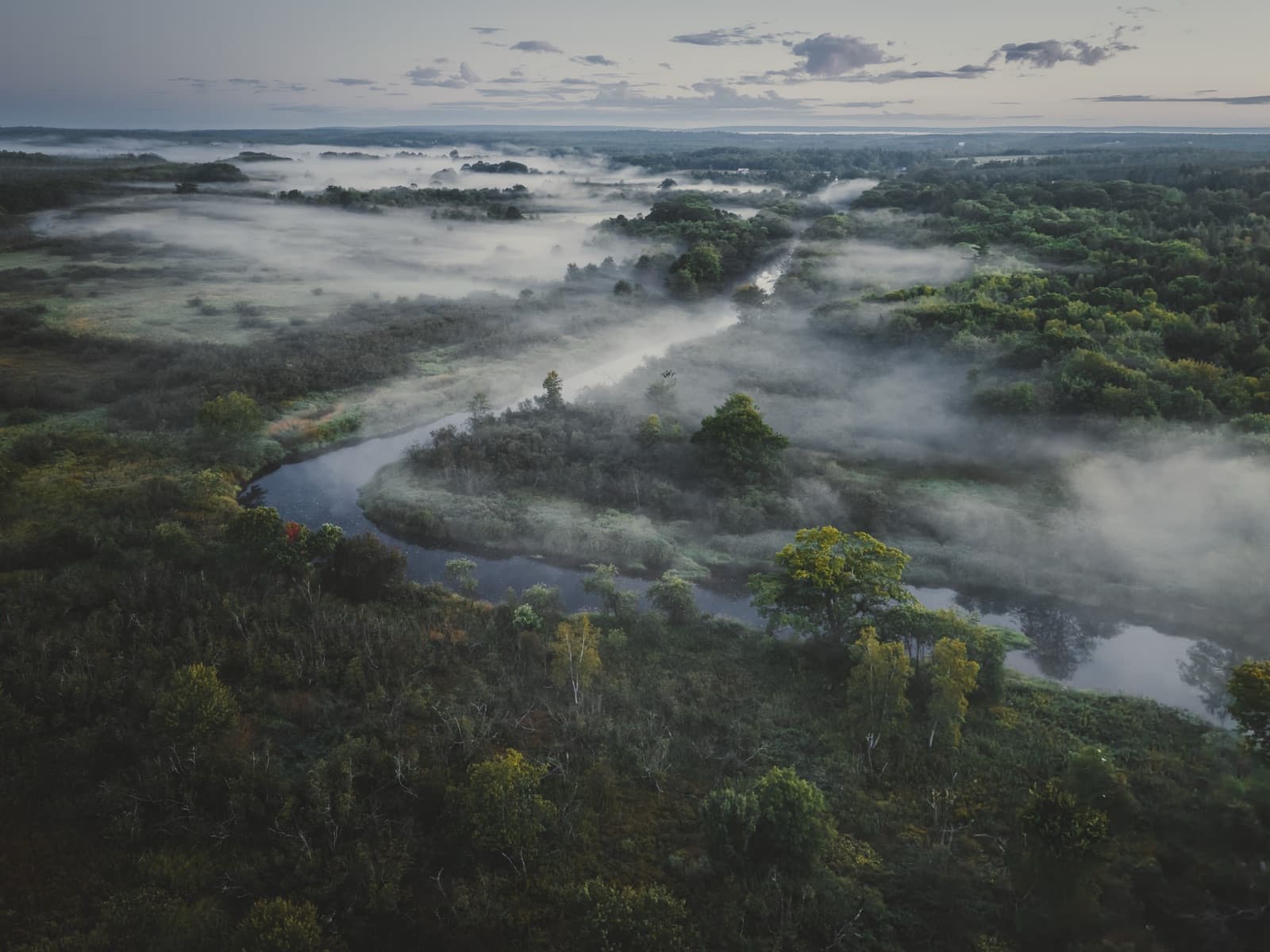 Misty river valley at dawn from above
